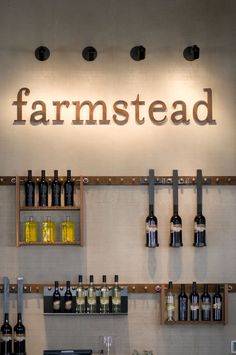 the bar is stocked with many bottles of wine and glasses on shelves that read, farmstead