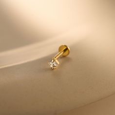 a pair of diamond earrings sitting on top of a white surface with light shining in the background