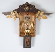 an ornate clock with gold leaf decorations on it's face and hands, hanging from the wall