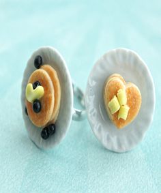 a pair of earrings with blueberries and bananas in the shape of heart on them