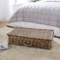 a wicker basket sitting on the floor next to a bed