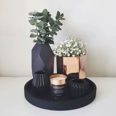 two vases with flowers in them sitting on a table next to some other items