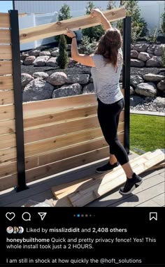 a woman holding up a piece of wood on top of a wooden deck