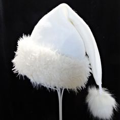 "Novelty Santa hat is made up in a creamy and cozy winter white or ivory tone poly fleece fabric. Hat is styled in the classic Santa slouch cone and is accented with a soft matching faux fur fabric turn up brim with a faux fur pompom on the top. Proportions of the hat are generous and will fit most head sizes, ladies or gents.  Measurement for opening for your head is 24-25\" circumference and the length is 20\". Check measurements to make sure this size will work for you.   Custom orders for si White Christmas Hat, White Mini Hats For Winter Party, White Short Brim Felt Hat For Winter, White Beanie Costume Hat For Winter, White Brimmed Felt Hat For Party, White Winter Beanie Costume Hat, White Beanie For Winter Costume, White Beanie For Winter Festival, White Brimmed Felt Hat For Winter