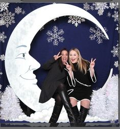 two women posing for a photo in front of a moon and snowflake backdrop