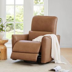 a brown recliner chair sitting in a living room next to a table with a potted plant on it