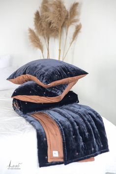 two pillows are stacked on top of each other in front of a vase with dry grass