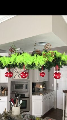 a kitchen decorated for christmas with ornaments hanging from the ceiling