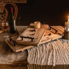 two wooden trays with candles sitting on top of a table next to wine bottles