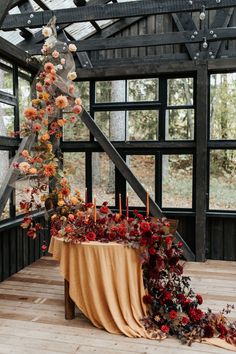 an arrangement of flowers and candles on a table in a room with wooden flooring