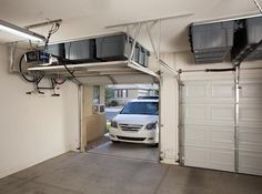 a car is parked in the garage with its door open and two overhead fans hanging from the ceiling