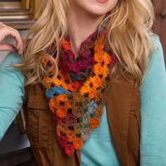 a woman with blonde hair wearing a multicolored crocheted scarf