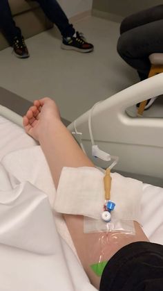 a person laying in a hospital bed with an iv tube attached to their arm and hand