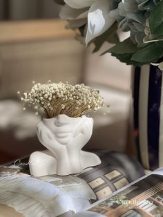 a vase filled with flowers sitting on top of a table next to an open book