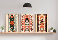 three framed art work displayed on a shelf