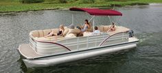 a group of people riding on the back of a white pontoon boat in a body of water