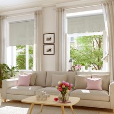 a living room filled with lots of furniture and flowers in vases on the coffee table