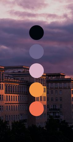 an image of a building with different colored circles in the sky above it at sunset