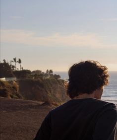 a man sitting on top of a beach next to the ocean