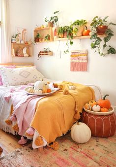 a bed with orange and pink blankets on top of it next to potted plants