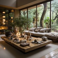 a living room filled with lots of furniture next to a large glass window covered in trees