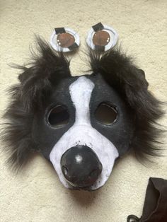 a black and white mask with long hair on top of a floor next to a pair of shoes