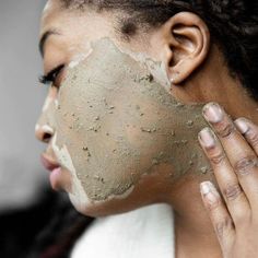 a woman with clay on her face and hand holding up the top of her face