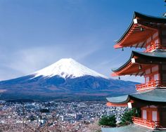 a tall building sitting in the middle of a city next to a snow covered mountain