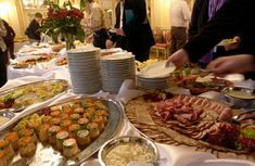 a buffet table filled with lots of food and people standing around the tables to eat