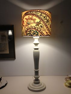 a lamp that is sitting on top of a table next to a framed picture and a painting