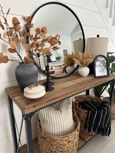 a wooden table topped with a mirror next to a basket filled with plants and vases