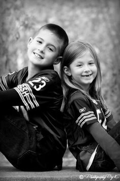 two young children sitting next to each other on the ground