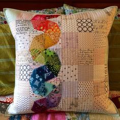 a close up of a pillow on a bed with many different colored pieces of fabric