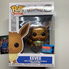 a gold pokemon pop vinyl figure in a box with an eevee sticker on it