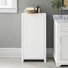 a white cabinet and sink in a room with grey walls, tile flooring and gray wallpaper