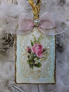 a glass ornament with a pink rose and pearls hanging from it's side