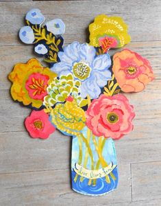 an arrangement of flowers in a blue vase on a wooden floor with buttons attached to it