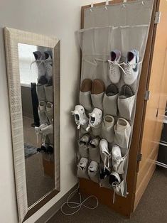 there are many pairs of shoes hanging on the wall next to a mirror and door