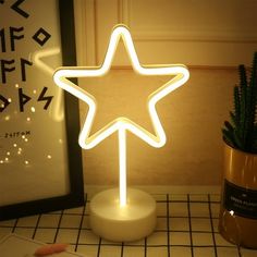 a star shaped light sitting on top of a table next to a potted plant