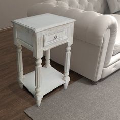 a white couch sitting next to a table on top of a hard wood floor