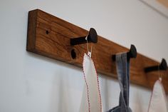 a pair of scissors hanging from a wooden hook on a wall next to clothes pins