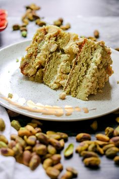 a white plate topped with two pieces of cake next to pistachios on a table