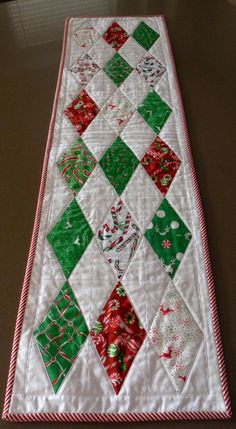 a quilted christmas table runner with red, green and white squares on the top