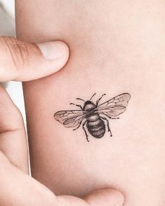 a small bee tattoo on the back of a woman's left arm is shown