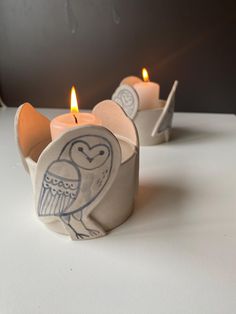 two candles are sitting on a table with one candle in the shape of an owl