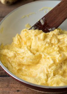 scrambled eggs in a bowl with a wooden spoon