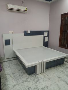 an empty bed frame in a room with pink walls and white furniture on the floor