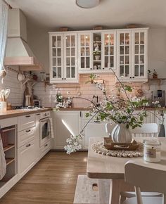 a kitchen filled with lots of white cabinets and counter top space next to a dining room table