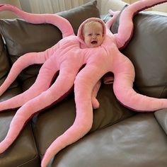 a baby in a pink octopus costume laying on a couch