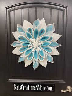 a blue and white paper flower on a black door